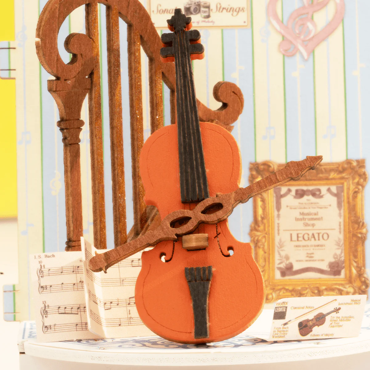 Detail view of curved window, cello and harp inside Rolife Melody Instrument Shop DS047